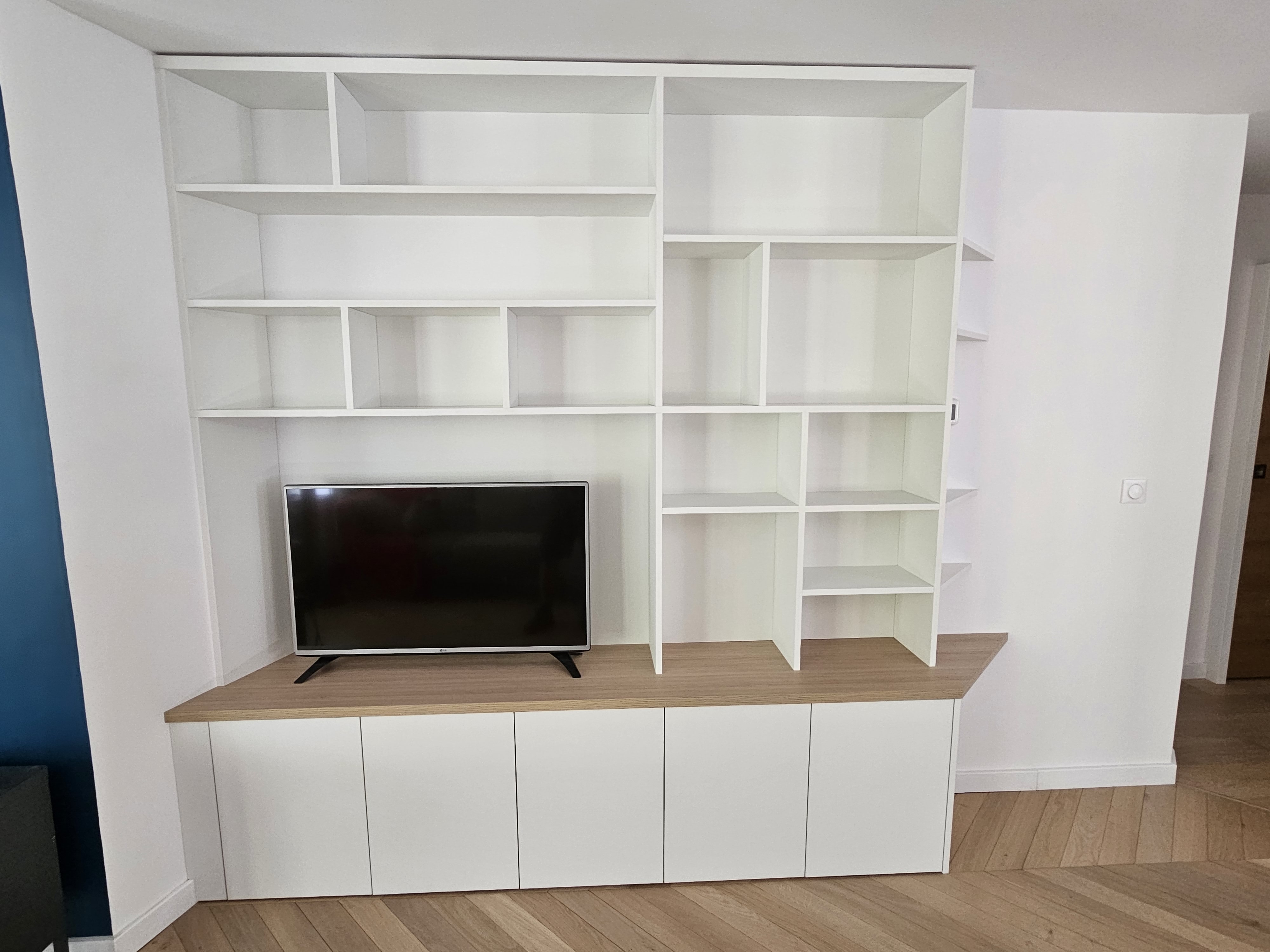 Placard sur mesure en bois avec portes coulissantes et étagères, offrant un espace de rangement optimal et élégant dans un salon.
