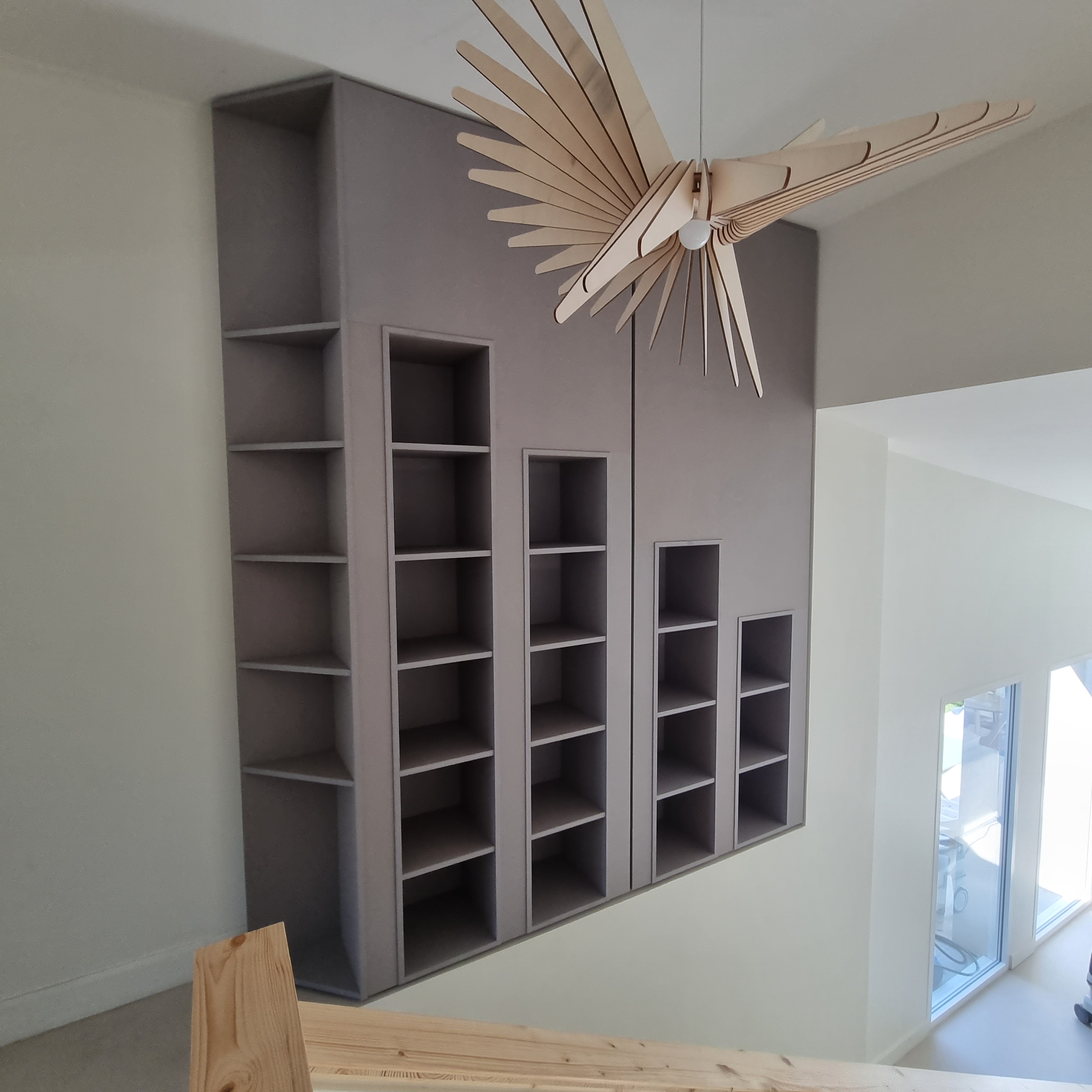 Bibliothèque sur mesure en bois avec étagères pour livres et objets décoratifs, optimisée pour un rangement personnalisé et esthétique dans un salon.